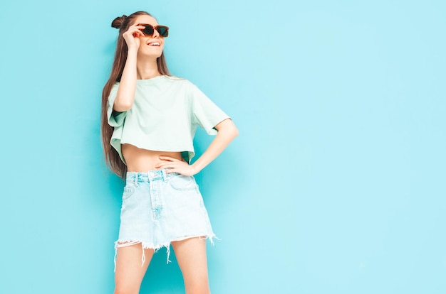 Free Photo young beautiful smiling female in trendy summer jeans skirt carefree woman posing near blue wall in studio positive model having fun indoors cheerful and happy