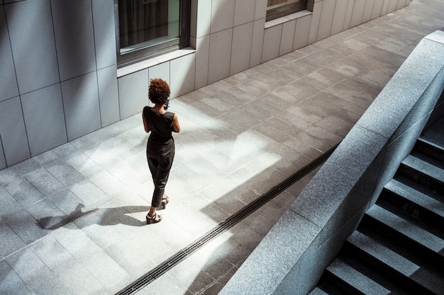 Free photo young beautiful woman walking down city