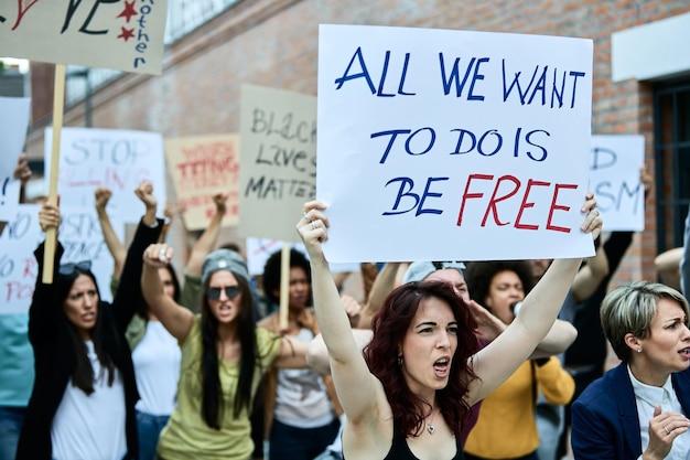 Free photo young caucasian woman carrying a banner while participating with crowd of people on public demonstrations