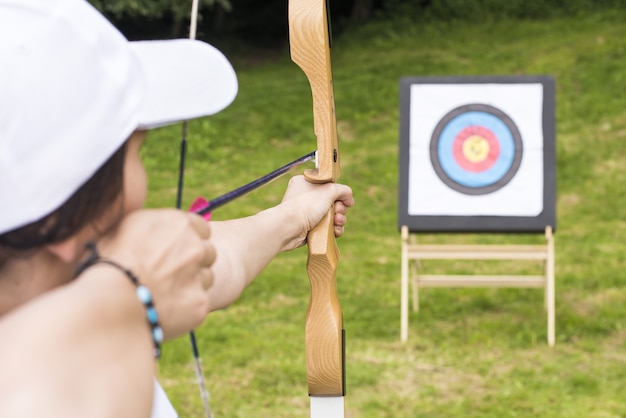 Free photo young female archer holding his bow aiming at a target - sport and recreation concept