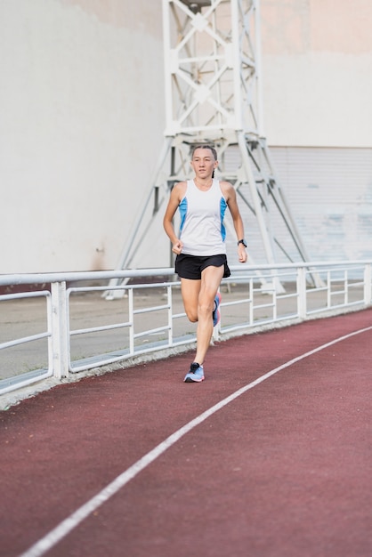 Free photo young female running at stadium