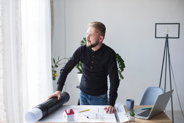 A young male architect in his office looking away