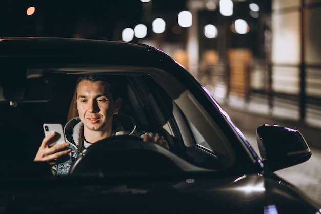 Free photo young man driving his car at a night time and talking on the phone