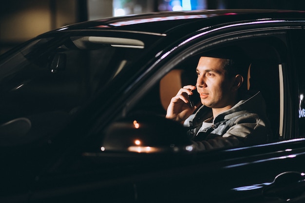 Free photo young man driving his car at a night time and talking on the phone