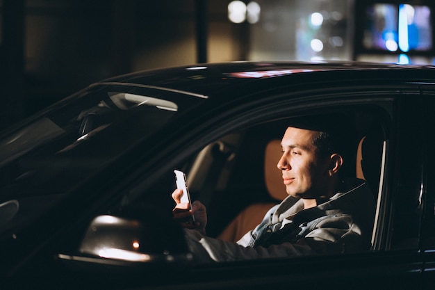 Free photo young man driving his car at a night time and talking on the phone