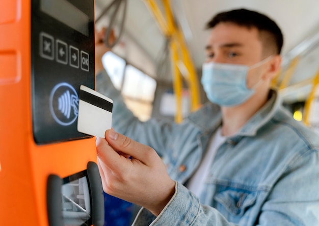 Free Photo young man travelling by city bus paying with bus card