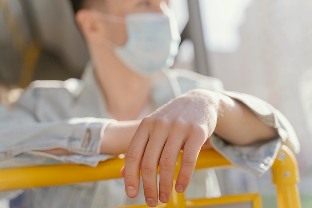 Free photo young man travelling by city bus wearing surgical mask