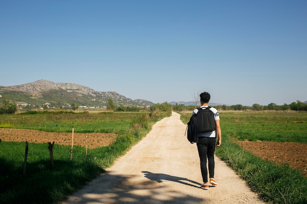 Free Photo young man walking on a nature trail with carrying backpack