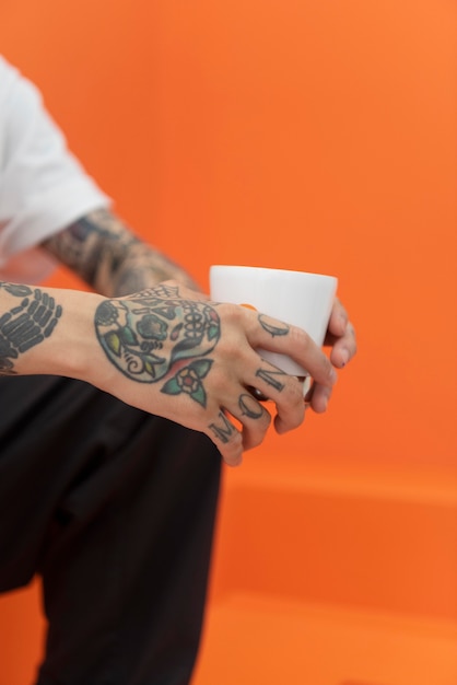 Young man with tattoos enjoying a cup of coffee at coffeehouse