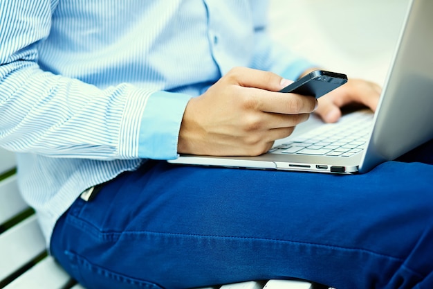 Free photo young man working with laptop, man's hands on notebook computer, business person in casual clothes in the street