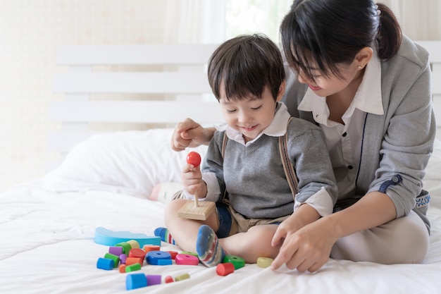 Free Photo young mother playing with lovely son in the bedroom