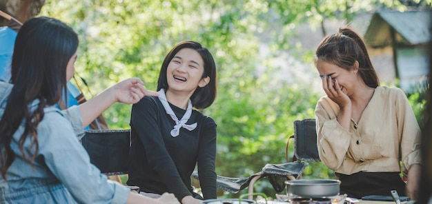 Free photo young pretty girl put an egg on pan while camping with her friends cooking easy meal in nature park they are enjoy to discussion and laugh with fun together copy space