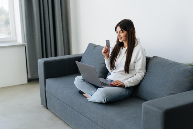 Young pretty woman working with laptop and credit card at home