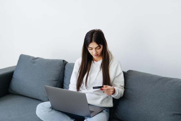 Young pretty woman working with laptop and credit card at home