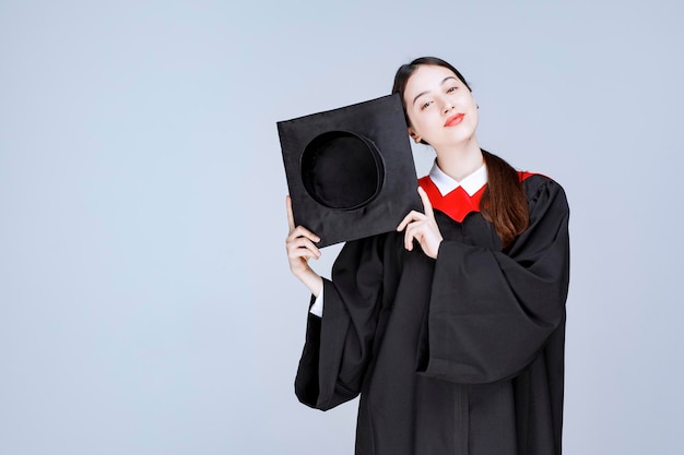 Free Photo young student in gown showing her graduation cap. high quality photo