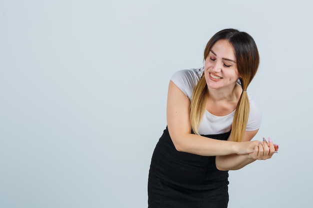 Foto gratuita giovane donna che stringe le mani e sembra allegra