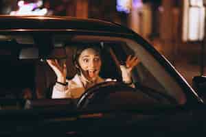 Free photo young woman driving in car at night