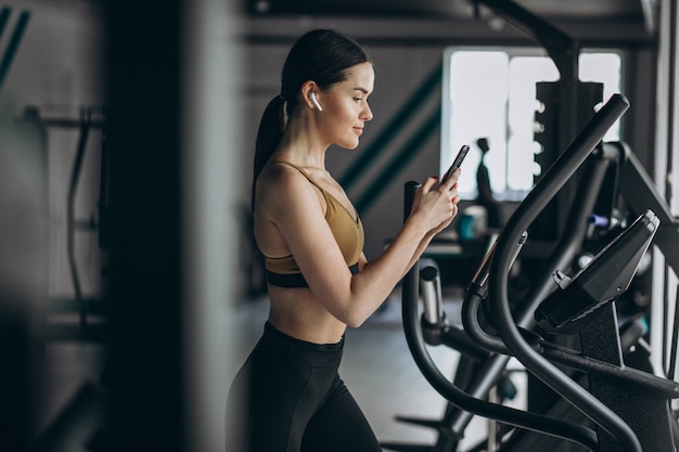 Free photo young woman exercising at gym on elliptical