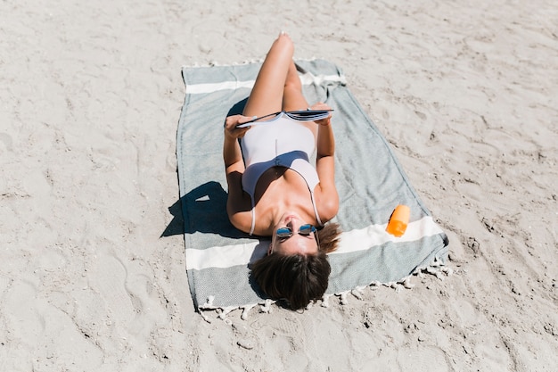 Free Photo young woman reading on sandy beach