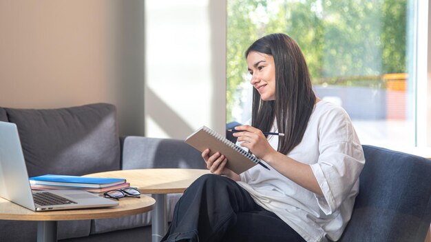 A young woman sits in front of a laptop and studies remotely