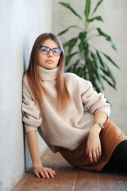 Free photo young woman sitting on the floor and posing