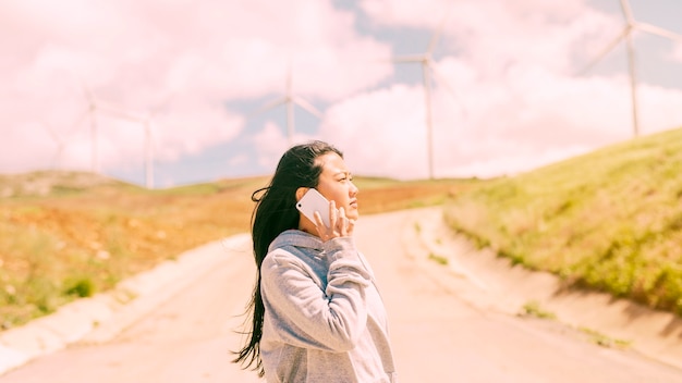 Бесплатное фото Молодая женщина разговаривает по телефону на проселочной дороге