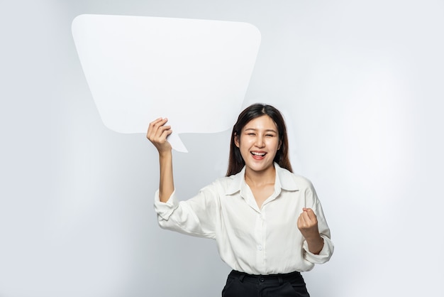 Free Photo a young woman in a white shirt holding a thought box symbol