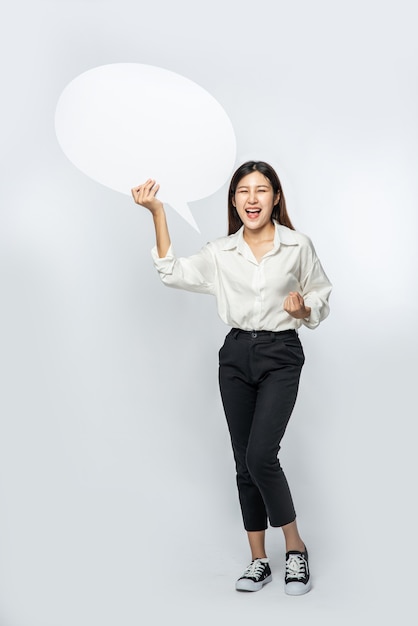 Free Photo a young woman in a white shirt holding a thought box symbol