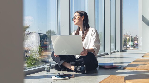 Young woman with a laptop at the window on a summer morning