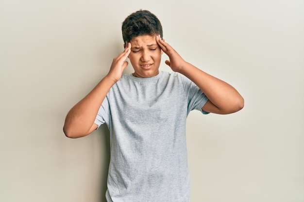 Photo gratuite adolescent hispanique portant un t-shirt gris décontracté avec la main sur la tête pour la douleur dans la tête à cause du stress. souffrant de migraine.