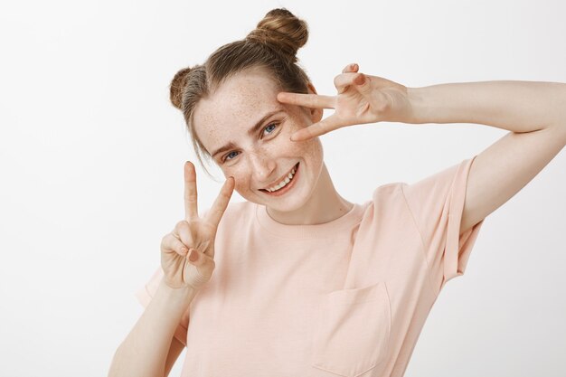 Adolescente rousse belle stupide et heureuse posant contre le mur blanc