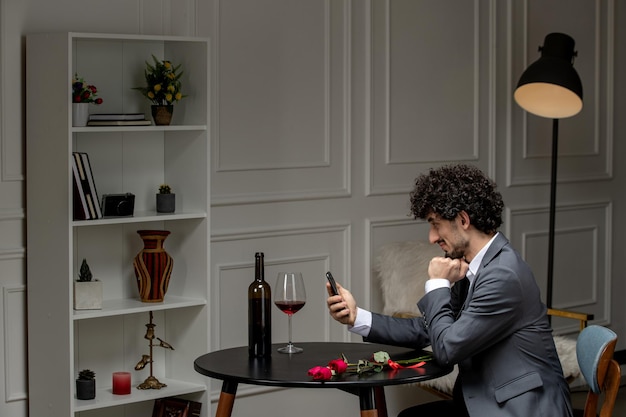 Photo gratuite amour virtuel beau mec mignon en costume avec du vin sur une date de téléphone à distance regardant vers le bas