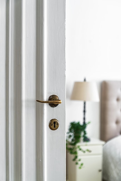 Photo gratuite ancienne serrure et bouton sur une porte en bois blanc de la pièce sous les lumières