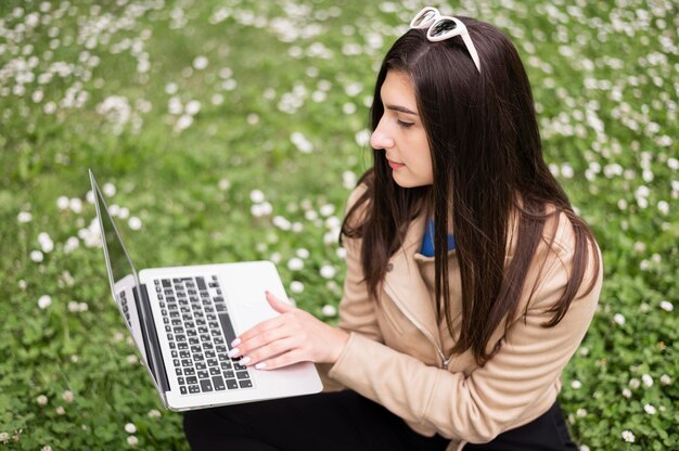 Angle élevé de femme travaillant sur un ordinateur portable à l'extérieur