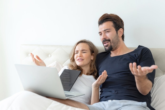 Beau mari et belle femme se sentent couple romantique en regardant des films depuis un ordinateur portable dans la chambre à coucher