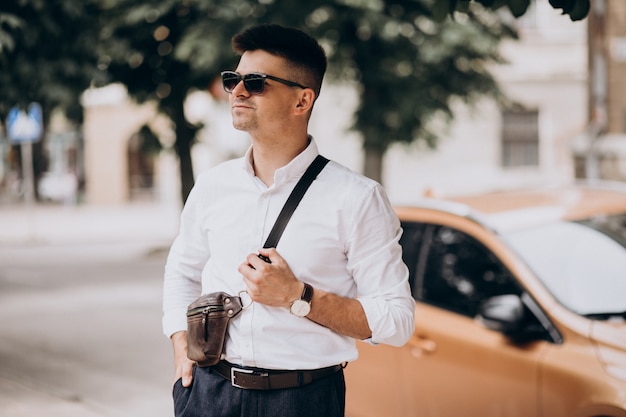 Photo gratuit bel homme d'affaires debout près de sa voiture lors d'un voyage d'affaires