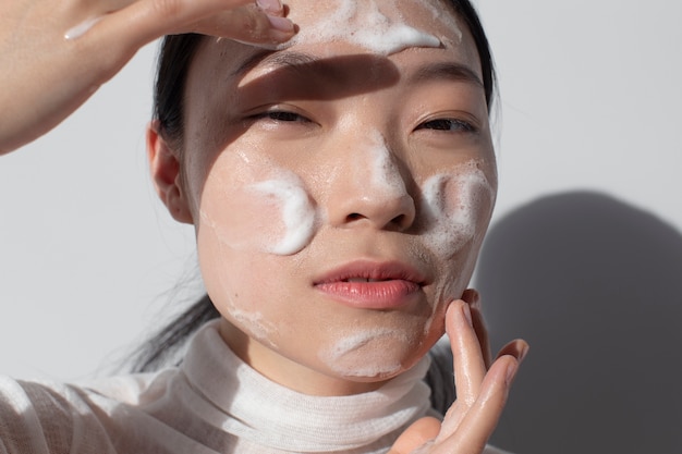 Photo gratuite belle femme asiatique posant avec de la crème pour le visage