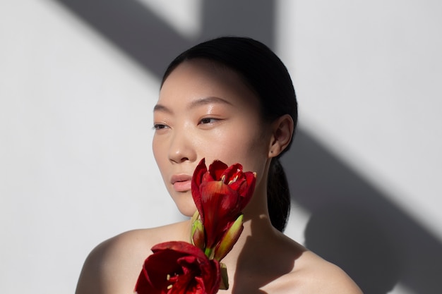 Photo gratuite belle femme asiatique posant tenant une rose avec une peau parfaite