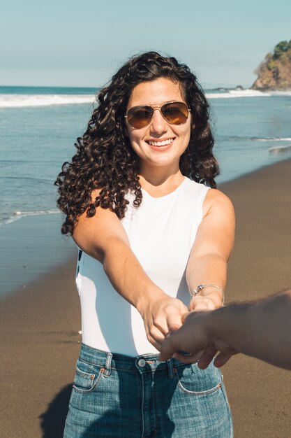 Belle femme souriante qui veut que son homme suive la plage