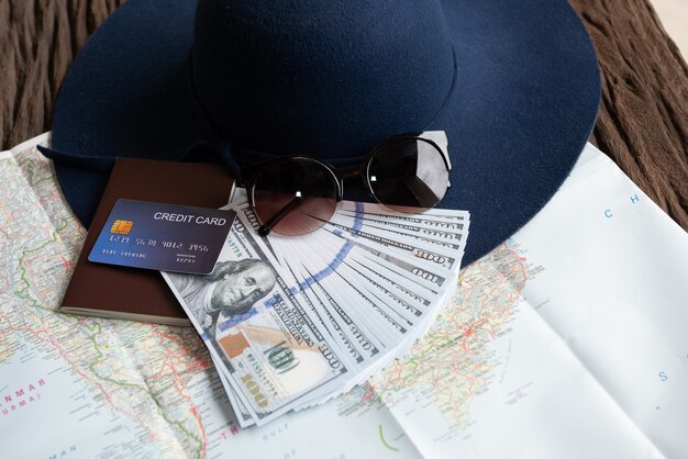 Billets de dollar, lunettes de soleil, carte de crédit, passeport et chapeau bleu