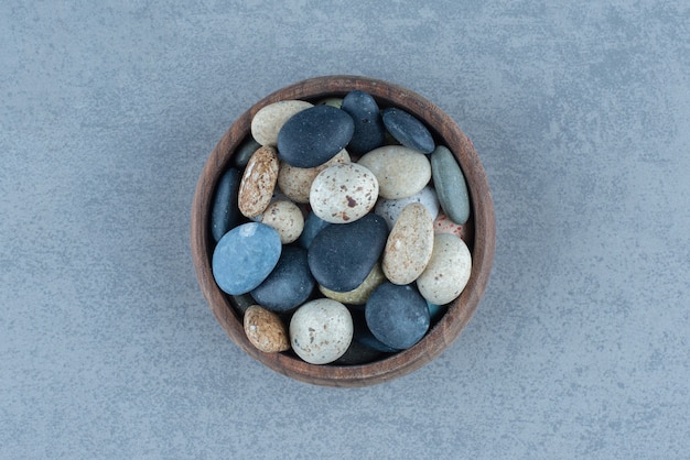 Photo gratuit bonbons en pierre de galets dans un bol, sur la table en marbre.