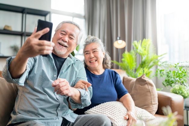 Photo gratuite bonheur asiatique vieux couple retraité senior profiter d'un appel vidéo à la famille ensemble sur un canapé dans le salon à la maison les gens asiatiques utilisent la communication par smartphone au concept d'ides d'isolement de la maison familiale