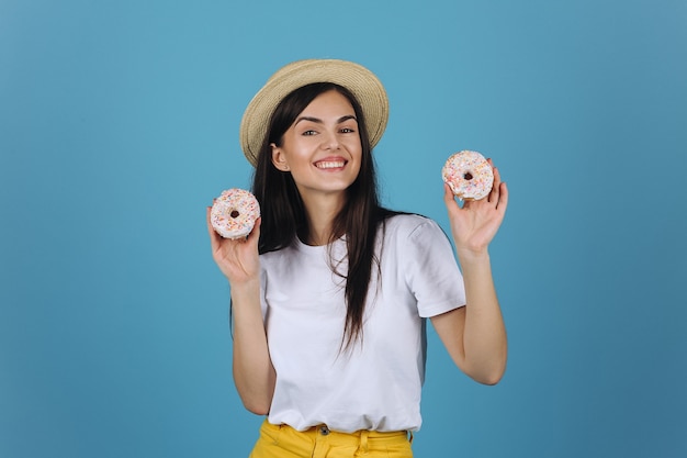 Photo gratuite brunette joyeuse s'amuse à poser avec des beignets délicieux dans le studio