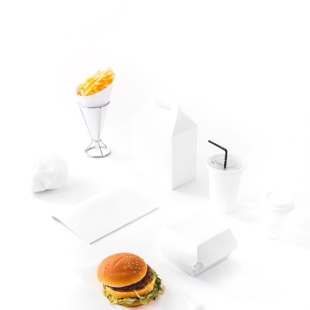 Photo gratuite burger; frites; boisson jetable et paquet de papier sur fond blanc