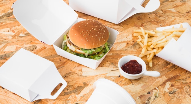 Photo gratuite burger; paquet de frites et de nourriture français mock up sur fond en bois