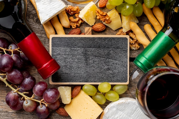 Photo gratuite cadre à côté de bouteilles de vin et de raisin et de fromage