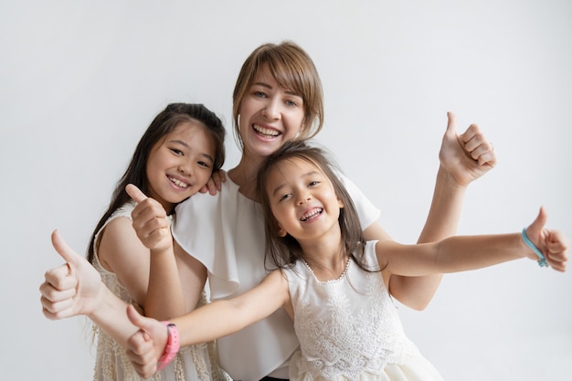 Photo gratuite caucasien positif mère et filles montrant les pouces vers le haut