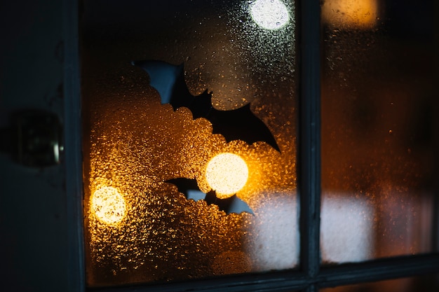 Chauves-souris décoratives d&#39;Halloween collées sur une fenêtre avec des gouttes de pluie