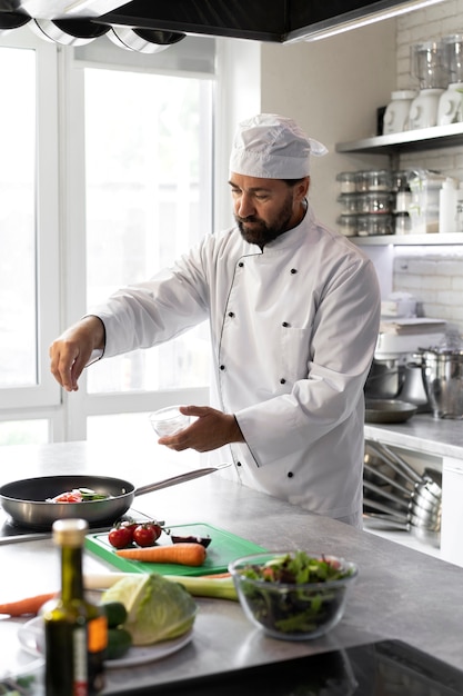 Photo gratuite chef masculin dans la cuisine faisant cuire le plat dans une poêle à frire