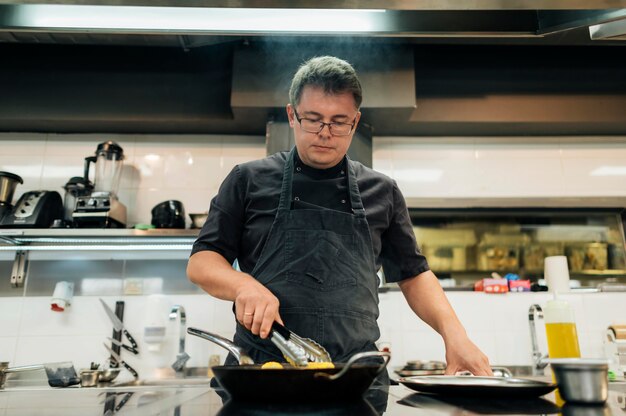 Photo gratuite chef masculin avec tablier de cuisson des pâtes